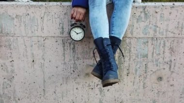 Doğanın arka planında bir kadının elindeki siyah çalar saat. Güzel bir kadının klasik siyah alarmını alıp dakikaların geçişini gösteren sonsuz ve zamansız konsept görüntüsü. konsepti yaşa ve tadını çıkar.