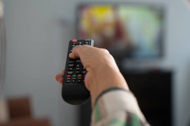 Evdeki kanepede otururken elinde uzaktan kumandayla son sınıf öğrencisinin fotoğrafını çek..