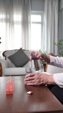 Evde yaşlı bir kadın günlük hapları ilaç organizatörüyle hazırlıyor.