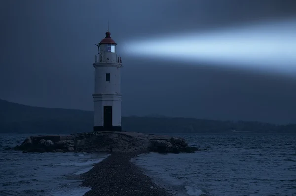 Farol em Vladivostok brilha à noite no mar Imagens De Bancos De Imagens