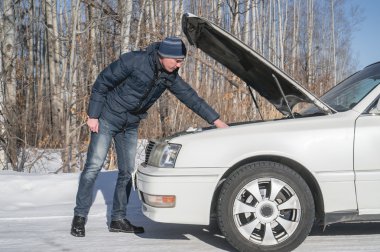 Adam beyaz bir araba onarır. Kırık araba