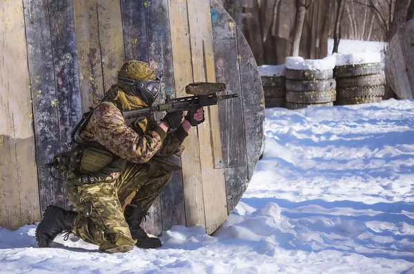 Um homem com um marcador de paintball é jogado no campo — Fotografia de Stock