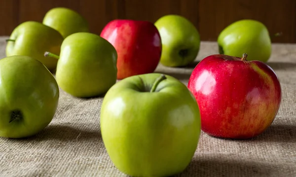 Apples scattered on the table, covered sackcloth — Stock Photo, Image