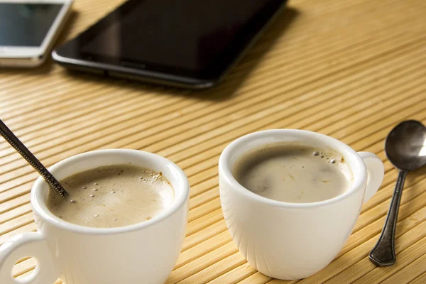 Deux tasses de café sur le bureau à côté de la tablette et m — Photo