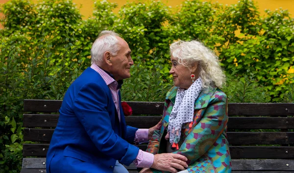 Пожилые мужчина и женщина сидят на скамейке и разговаривают . — стоковое фото