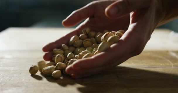 Handen van een jonge chef-kok die van enkele van de smakelijke pistachenoten Bronte in extreme slowmotion loslaten — Stockvideo