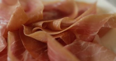 Macro of spinning thin slices of pork ham on the dish (close up)