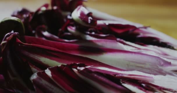 Macro cerrar deslizador de jugosas rodajas de achicoria húmeda fresca en una mesa de cocina de madera — Vídeos de Stock