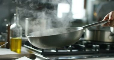 Super slow motion macro of middle aged chef preparing tagliolini with black truffle in a pan in restaurant kitchen