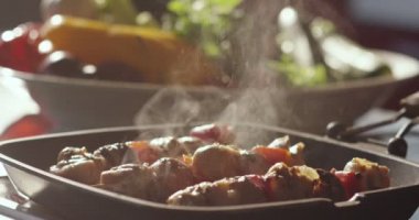 Super slow motion of he of meat with vegetables cooked on a spit in a pan (close up)