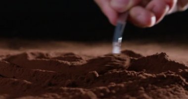 Süper ağır çekim kakao tozu dozaj, küçük bir kaşıkla 4 k siyah bir zemin üzerine izole (makro kapat)