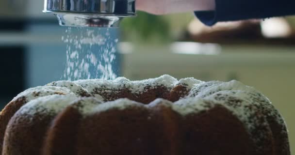 Macro Super cámara lenta de un hombre de mediana edad panadero espolvorear azúcar blanco en polvo en un pastel (de cerca ) — Vídeos de Stock