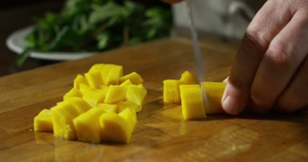 The knife of an expert chef size of the cubes of pineapple for the preparation of a dessert likely — Wideo stockowe