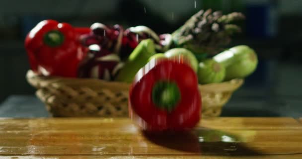 Red paprika fall fresh and dripping water on a professional wooden chopping board colorful kitchen — Αρχείο Βίντεο