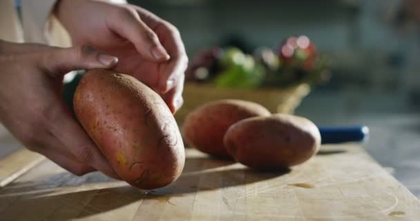 Руки молодого шеф-повара ласкают боковую сторону картины красную картофельную приаму, которую режут на кухне на деревянной доске — стоковое видео