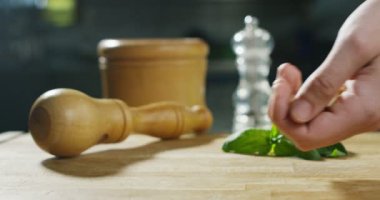 bir deneyimli şef dokunmatik hakiki edilmeden önce kalite kontrol etmek için çamfıstıklı elinde ünlü İtalyan pesto genova, arka plan üzerinde gelen bazı eski spin rulo ve fesleğen yaprakları pişmiş.