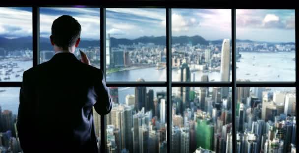 Firar en framgångsrik ung man på toppar i en glasbyggnad med Wallstreet landskap och samtal med sin smartphone — Stockvideo