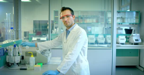 Jeune et charmant accomplit quelques procédures médicales de routine et équipé professionnel dans le chercheur de laboratoire avec des matériaux de perfectionnement professionnel — Video