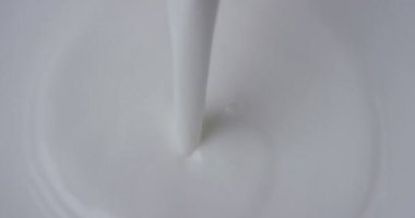 Super slow motion macro of milk drops pouring in the bowl (close up) 4k