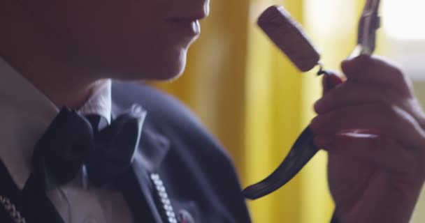 Slow motion of young sommelier dressed in formal jacket and tie smells and tries white wine poured in transparent glass — Stock Video