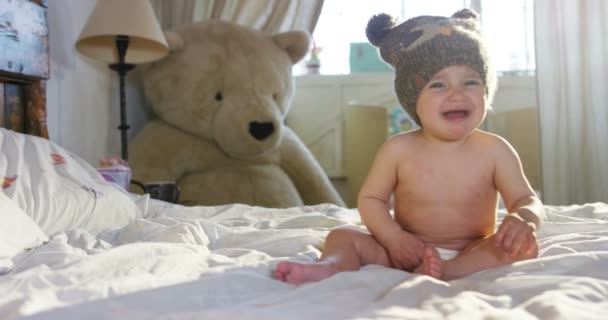 En söt liten baby tittar in i kameran och är klädd i en brun hatt, barnet ser sig omkring och leka med armarna — Stockvideo