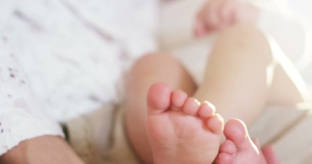 The hands of a mother gently touch her baby feet while breastfeeding — Stock Video