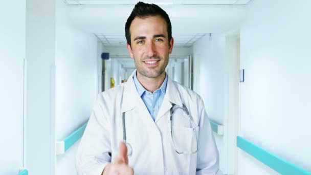 Charmant jeune médecin regarde dans la caméra dans un élégant couloir clinique souriant et donnant une expression de sécurité dans son travail — Video