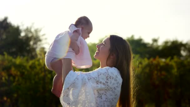 Belle jeune mère jouant avec la petite fille affectueusement tandis que le soleil couchant se couche dans un bel environnement naturel — Video