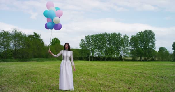 Frau mit Luftballons auf der Wiese — Stockvideo