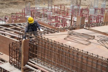 İnşaat alanında çalışan işçiler çelik yapıdan su döküyorlar.