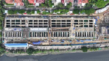 Arka planında vinç ve büyük bir bina olan hava manzaralı bir inşaat alanı. Vinç görüntünün sol tarafında ve bina da sağ tarafında. şehir merkezi 