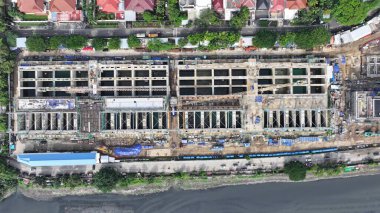 Arka planında vinç ve büyük bir bina olan hava manzaralı bir inşaat alanı. Vinç görüntünün sol tarafında ve bina da sağ tarafında. şehir merkezi 