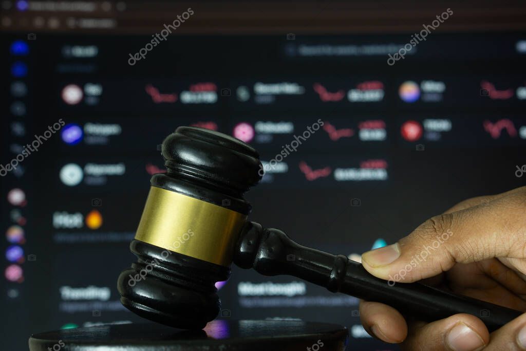 Dhaka, Bangladesh- 20 June 2025: A hand holds a gavel in front of a computer screen displaying Kraken's website