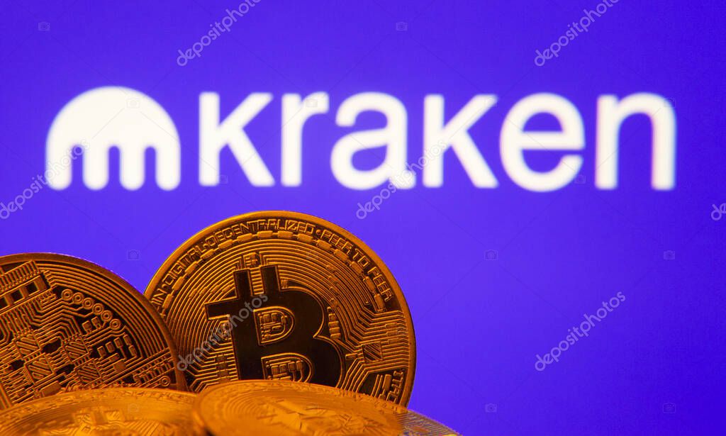 Dhaka, Bangladesh- 01 Nov 2025: Close-up of Bitcoin coins with the Kraken logo visible on a screen in the background.