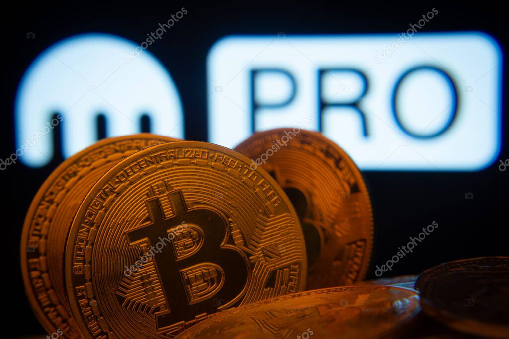 Dhaka, Bangladesh- 01 Nov 2025: Close-up of Bitcoin coins with the Kraken Pro logo visible on a screen in the background.