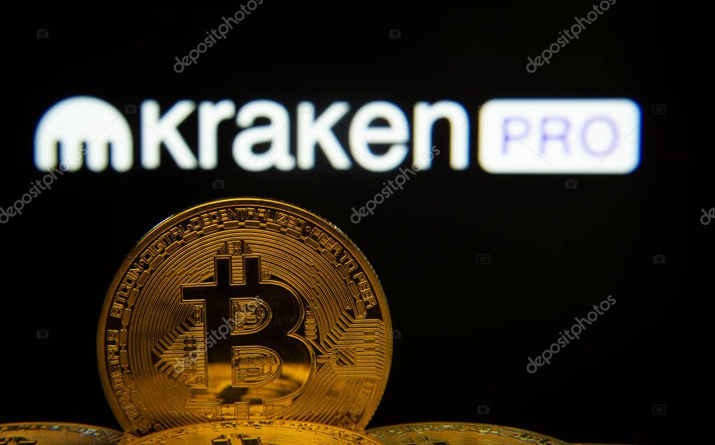 Dhaka, Bangladesh- 01 Nov 2025: Close-up of Bitcoin coins with the Kraken Pro logo visible on a screen in the background.