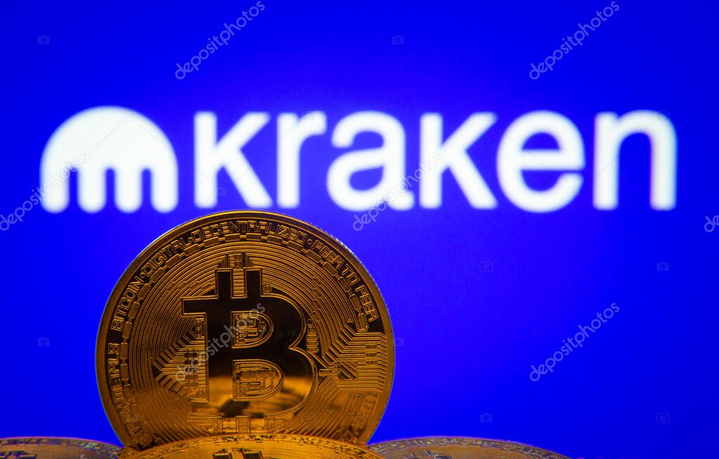 Dhaka, Bangladesh- 01 Nov 2025: Close-up of Bitcoin coins with the Kraken logo visible on a screen in the background.