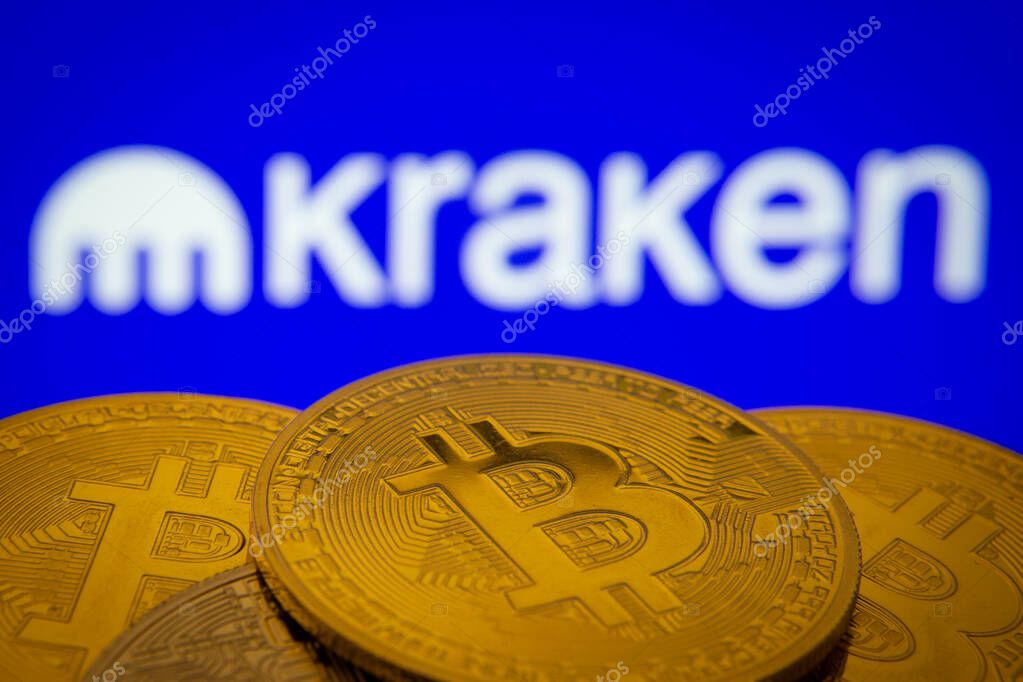 Dhaka, Bangladesh- 01 Nov 2025: Close-up of Bitcoin coins with the Kraken logo visible on a screen in the background.