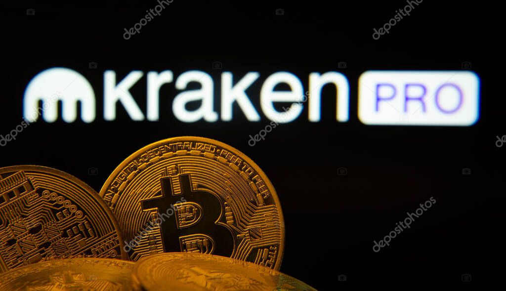 Dhaka, Bangladesh- 01 Nov 2025: Close-up of Bitcoin coins with the Kraken Pro logo visible on a screen in the background.