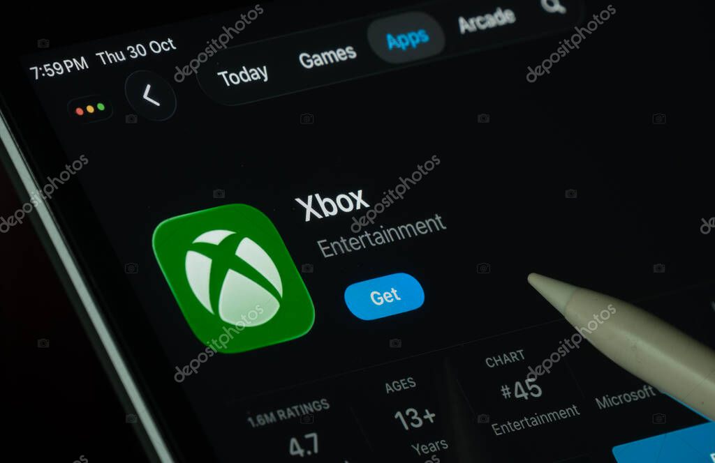 Dhaka, Bangladesh- 30 Oct 2025: Xbox app displayed on a iPad screen in dark mode with a digital pen pointing at it.
