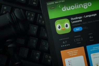 Dhaka, Bangladesh- 28 Oct 2025: An iPad displaying the Duolingo app against a judge's gavel and dark keyboard background.