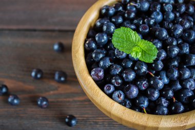 ahşap masa üzerinde bir kasede yaban mersini