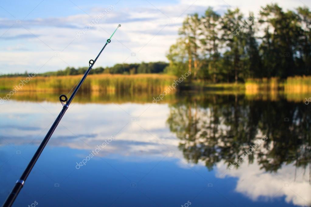 Fishing rod in hand on a background of lake — Stock Photo © detry