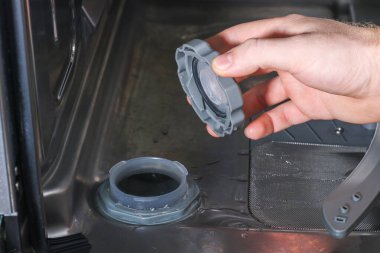 Adam bulaşık makinesindeki tuz için kabı açar ve orada özel bir tuz doldurur..