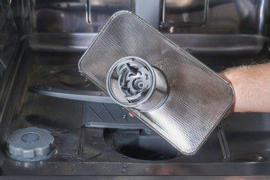 Adam bulaşık makinesindeki filtreyi söküyor..