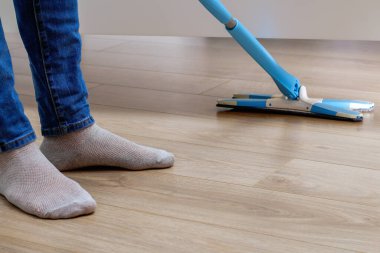 Bir adam odada paspasla yerleri yıkıyor. Yatağın altında. Temizlik.