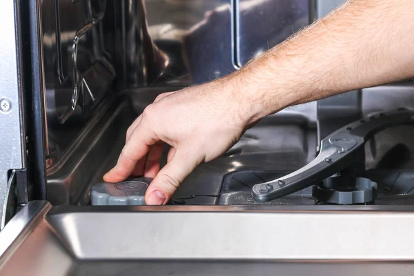 Homem abre o recipiente para sal na máquina de lavar louça e preenche sal especial. — Fotografia de Stock