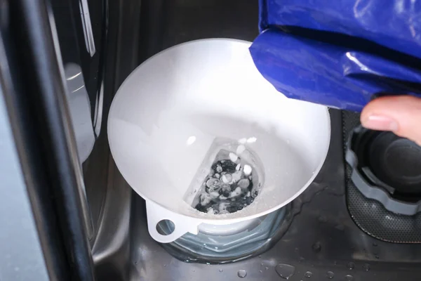 Homem abre o recipiente para sal na máquina de lavar louça e preenche sal especial. — Fotografia de Stock