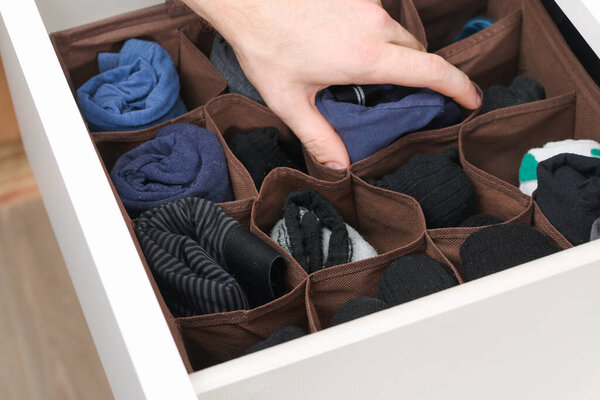 A man takes socks and panties folded according to the method of Marie Kondo. Vertical storage of
