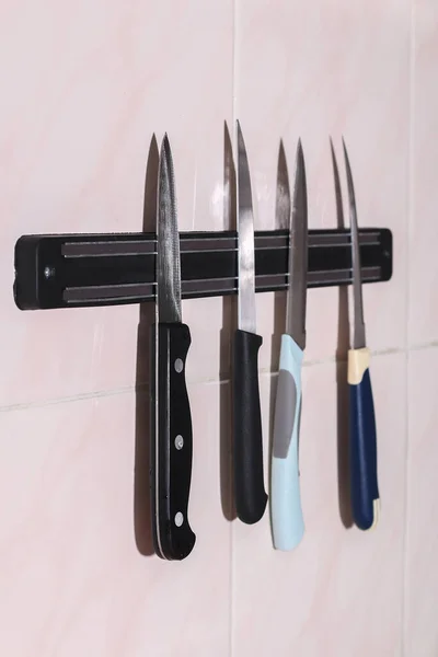 A man takes a knife from magnetic kitchen holder for knives, scissors, metal tools. — Stock Photo, Image